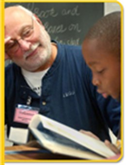 A volunteer helps a student with a reading lesson